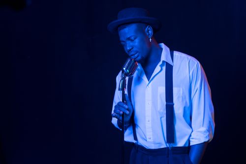 Free A male vocalist passionately sings under blue stage lighting, exuding emotion and style. Stock Photo