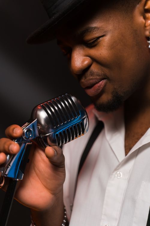 Free Emotional close-up of a black male singer holding a vintage microphone during a performance. Stock Photo
