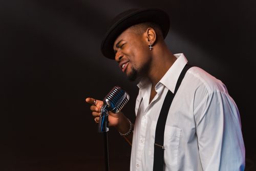 Free A passionate male singer performing with a vintage microphone, expressing deep emotions on stage. Stock Photo