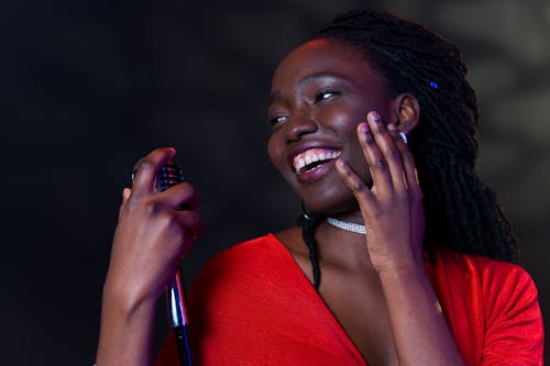 Close Up Photo of Woman Smiling While Holding a Microphone