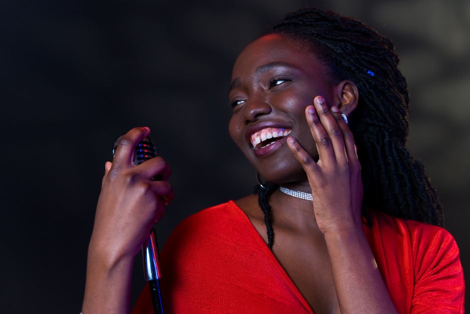 Portrait of a smiling singer holding a microphone, expressing joy and happiness.