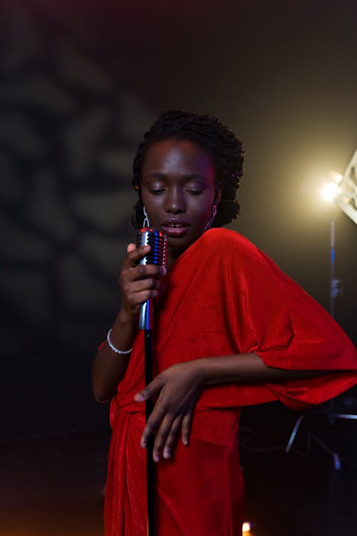 Woman in Red Dress Holding Microphone While Looking Down