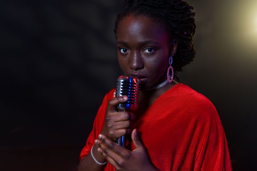 A talented female singer in a red dress performing on stage with a vintage microphone.