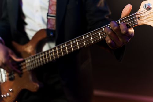 Free A musician elegantly playing an electric bass guitar on stage, focus on hands and instrument. Stock Photo
