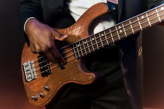 Focused view of a musician playing a wooden bass guitar on stage.
