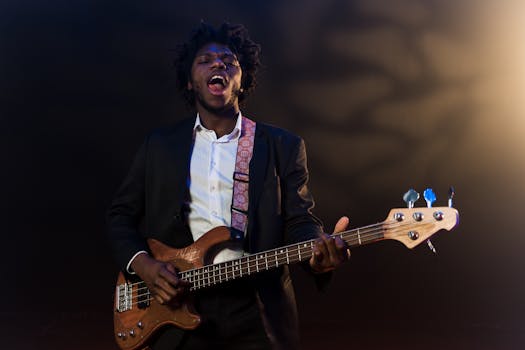 A black musician passionately performing with a bass guitar on stage under spotlight.