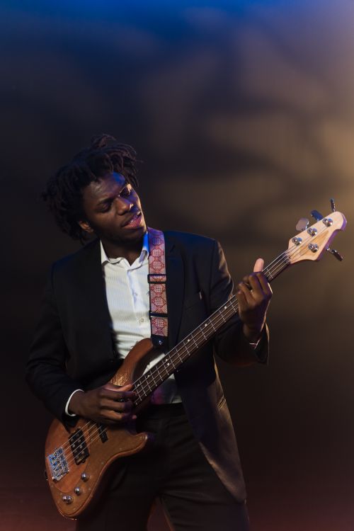 Free African American musician playing electric guitar with passion on a dimly lit stage. Stock Photo