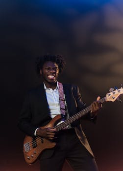 African-American man in suit passionately playing electric guitar on stage, highlighting musical expression.