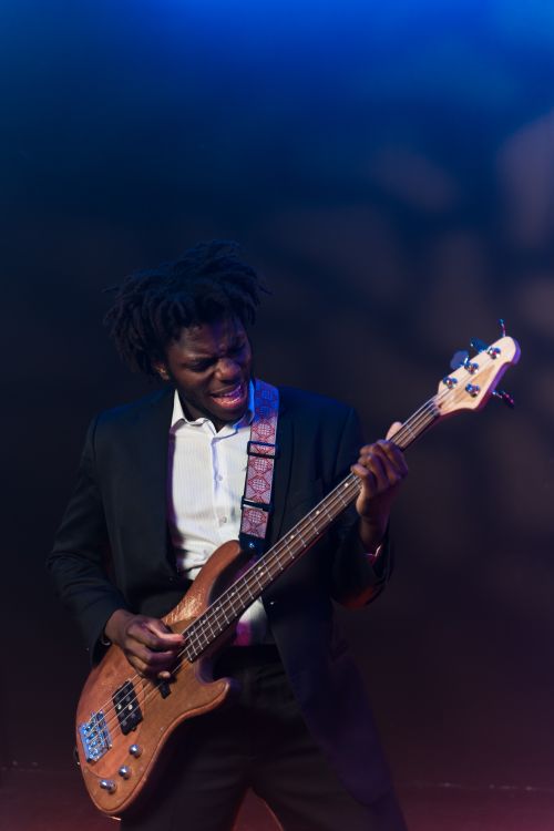Free Dynamic African American guitarist passionately playing electric guitar on stage. Stock Photo