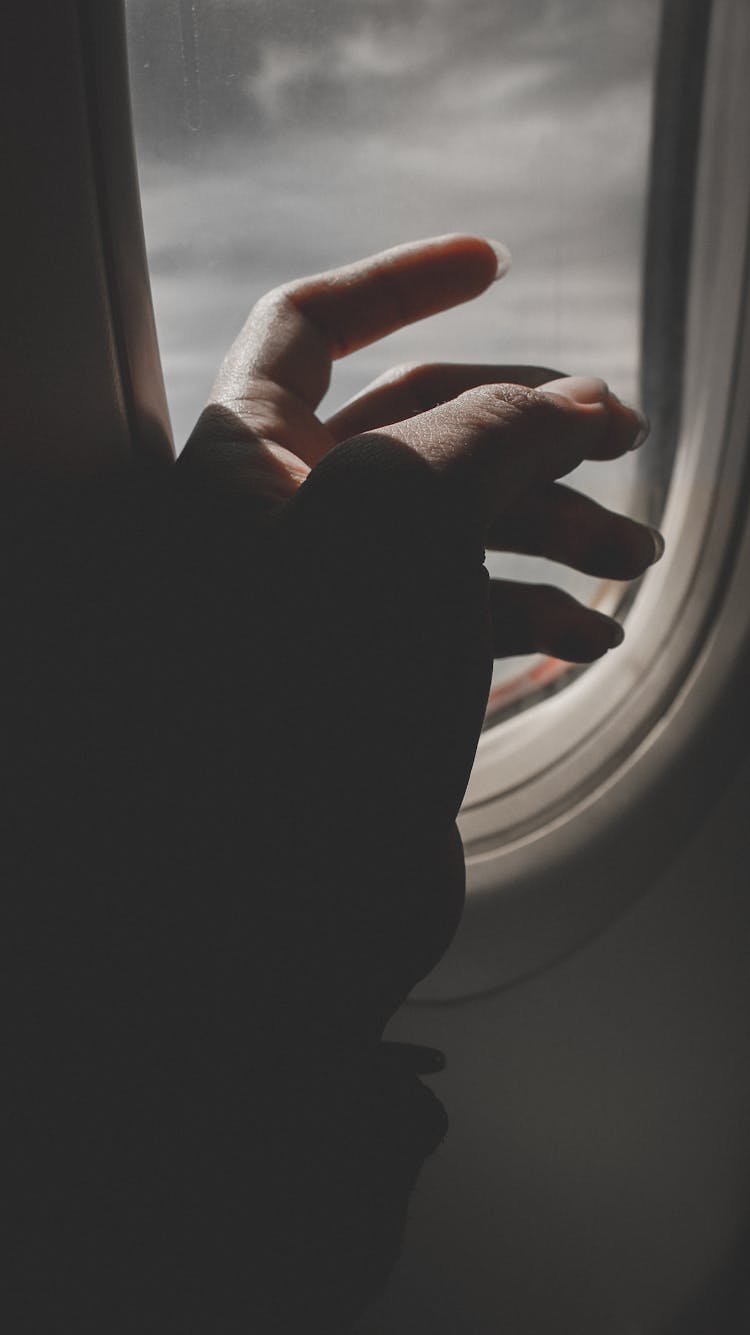 Hand By Airplane Window 