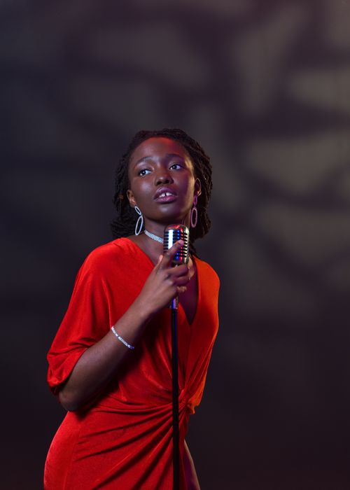 Free Captivating portrait of a female vocalist holding a vintage microphone, exuding emotion and style. Stock Photo