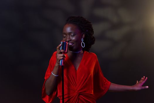 An elegant female singer in a vibrant red dress performs passionately with a vintage microphone.