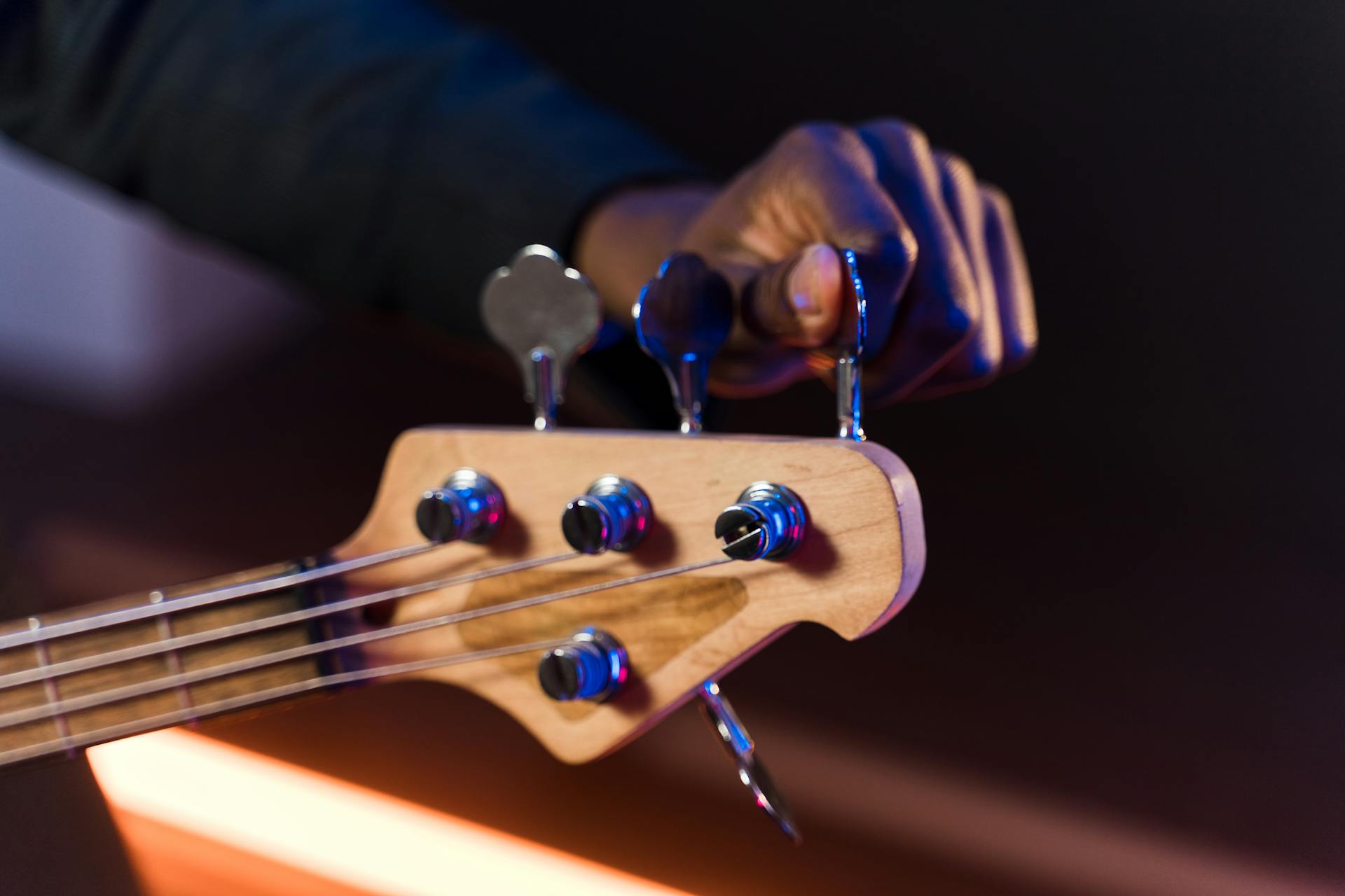 A Person Holding the Tuning Key of an Acoustic Guitar