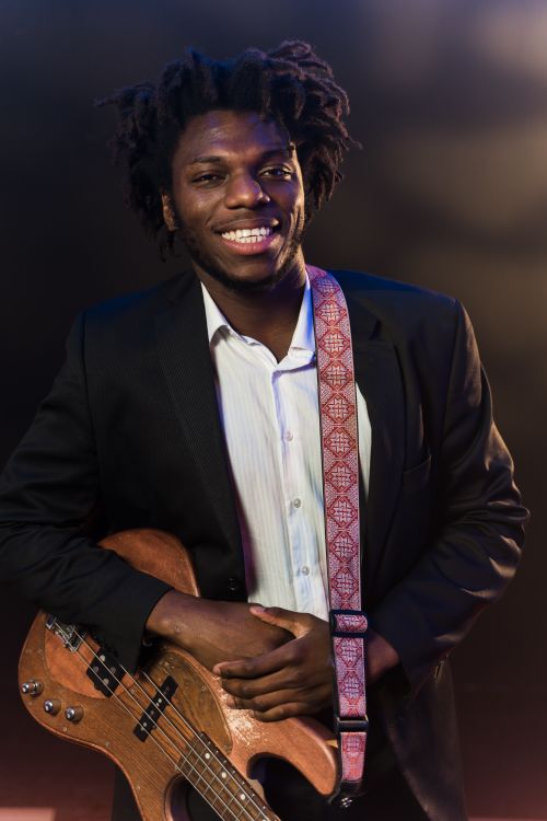 Free Cheerful guitarist in suit holding electric guitar under stage lights. Stock Photo