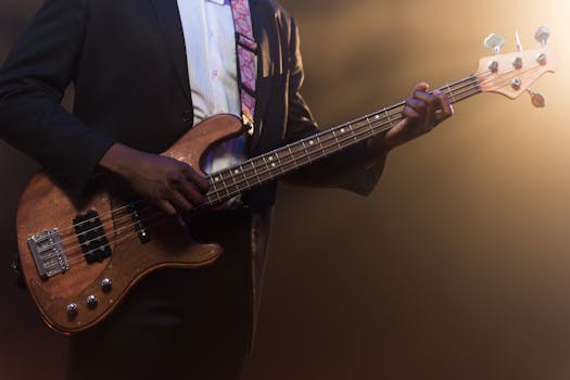 A musician in a suit playing a bass guitar on stage under warm lighting.