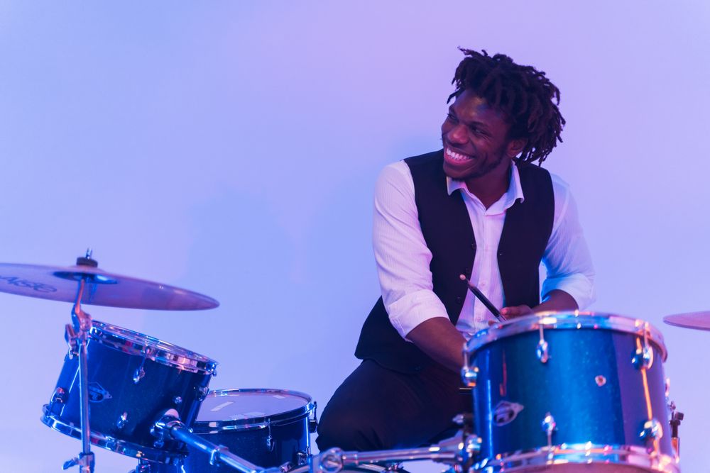 Caleb Hamilton smiling while playing the drum kit in his home studio