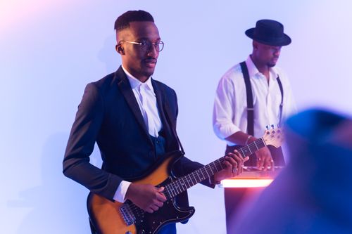 Free Stylish African American musician playing electric guitar on stage with a keyboardist. Stock Photo