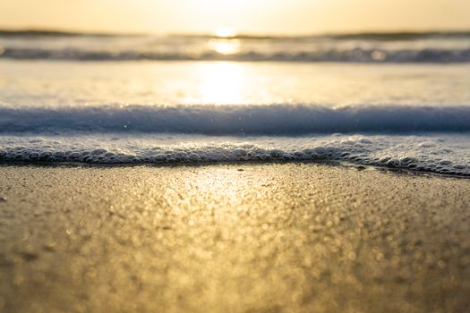 Golden sunlight reflecting on a serene beach shoreline at sunrise.