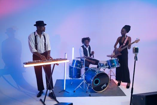 A lively band performing with drums, keyboard, and bass guitar under colorful lights.