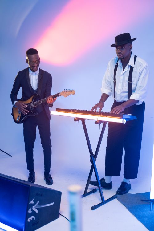 Free Two musicians performing with electric guitar and keyboard under vibrant lighting. Stock Photo