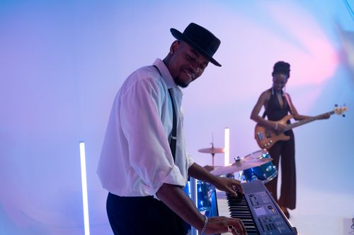Free Energetic performance by a duo with electric keyboard and bass guitar under colorful lighting. Stock Photo