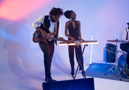 Free A lively band playing bass guitar and keyboard under colorful stage lights. Stock Photo