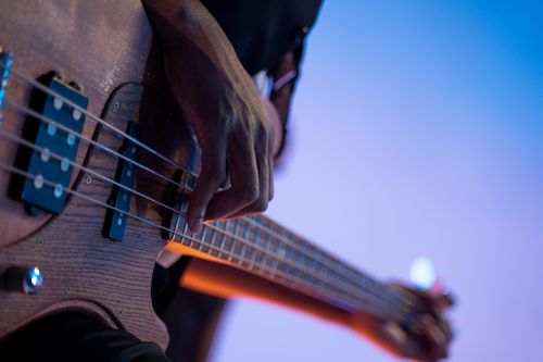 Free Close-up of a musician playing an electric bass guitar under vibrant stage lights. Stock Photo