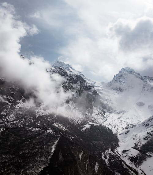 Snow Covered Mountain Under Low Clouds and Gray Sky