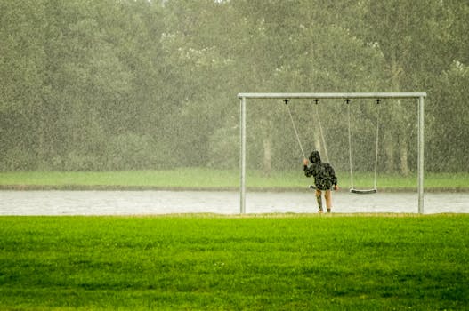 一个孩子在多雨的公园里荡秋千，捕捉到了如雨点般宁静的瞬间
