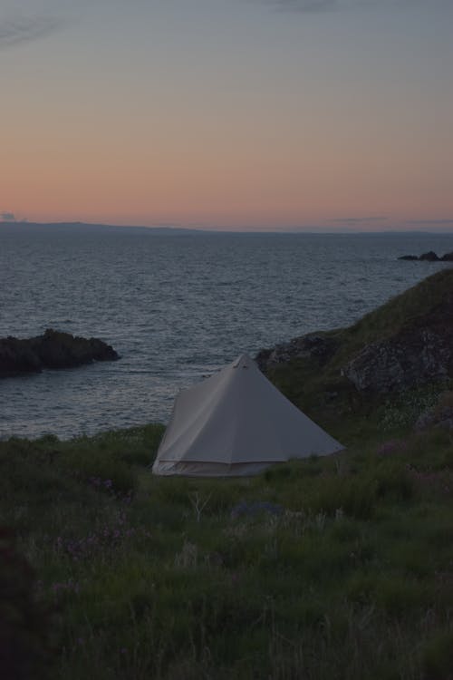 White Tent on Green Grass Field Near Body of Water