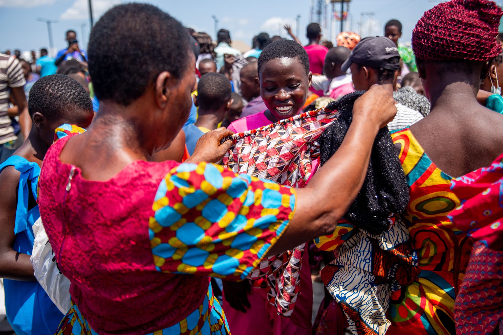 Colorful outdoor market scene with African women trading textiles under the sun.