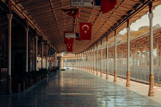 A deserted Turkish train station with hanging flags and metallic columns.