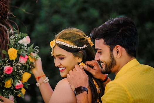 A joyful Indian couple shares a candid moment during a vibrant wedding ceremony, adorned with colorful flowers.