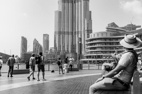 A Grayscale Photo of People Walking on the Street Near the Buildings