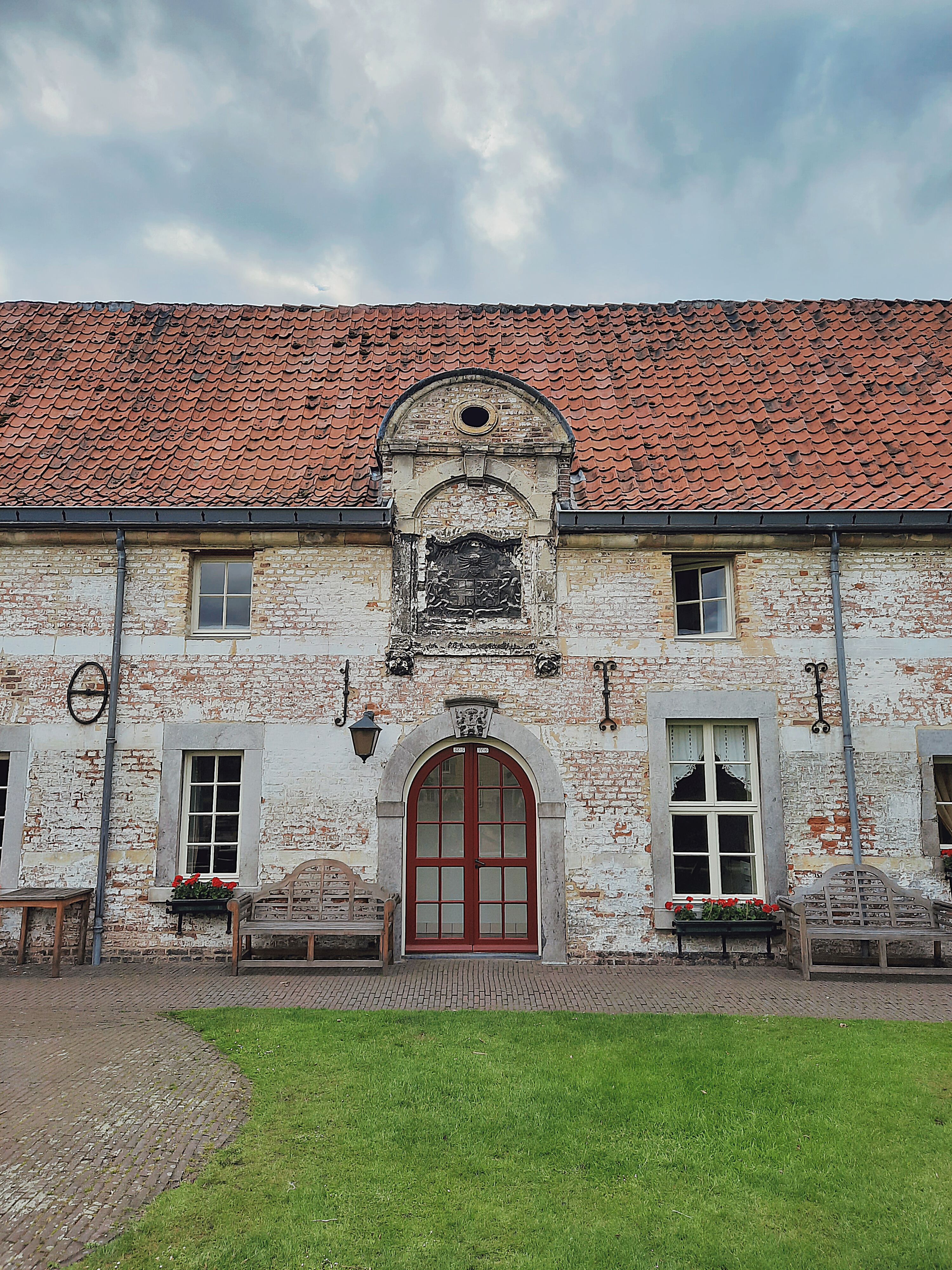 Historic building with a vintage arched doorway and rustic brick facade under a cloudy sky.
