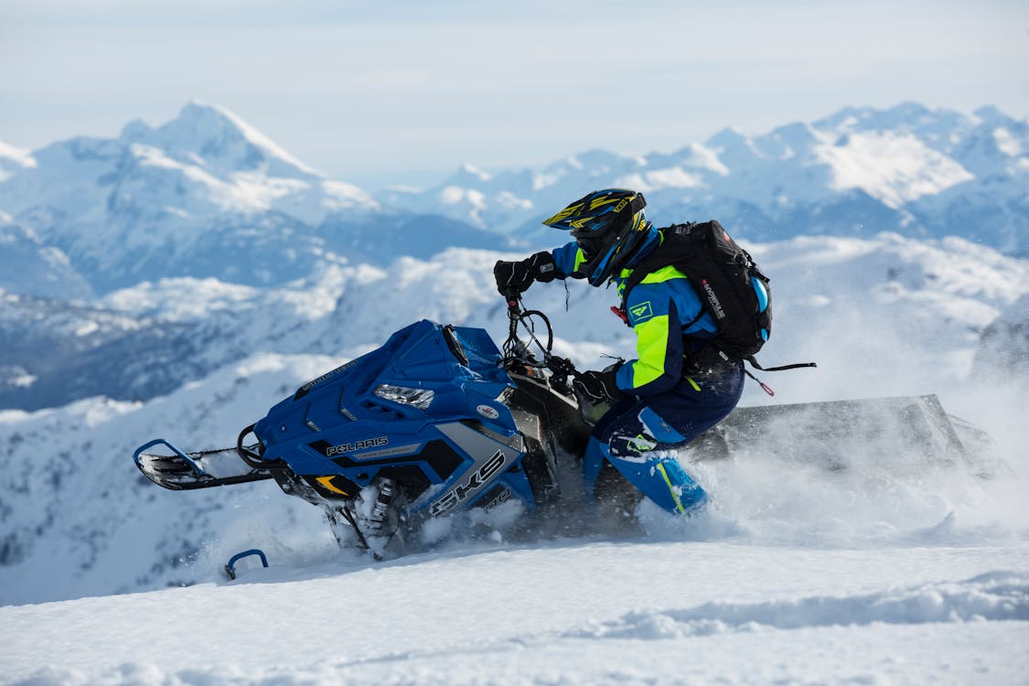 Free Man In Blue And Green Long-sleeved Suit Riding On Snowmobile Stock Photo