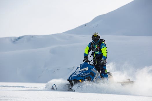 A person riding a snowmobile through a snowy mountain landscape in winter.