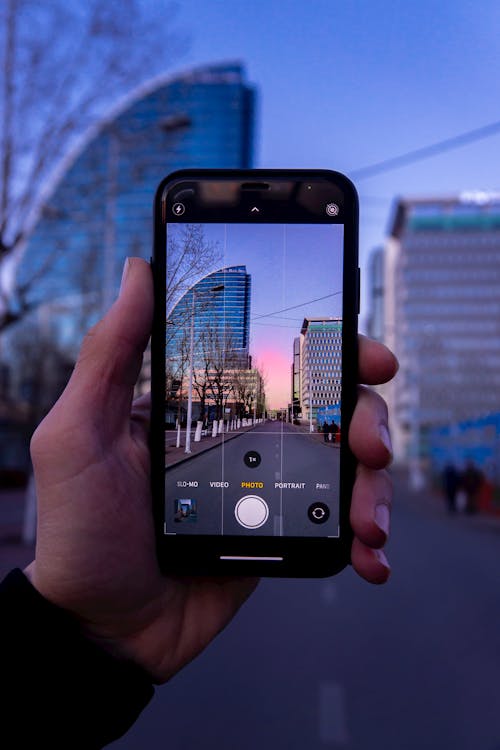 Free Person Holding Black Iphone 5 Taking Picture of City Skyline Stock Photo
