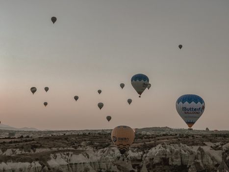Breathtaking view of hot air balloons flying over canyons at sunrise, showcasing a serene and vibrant landscape.