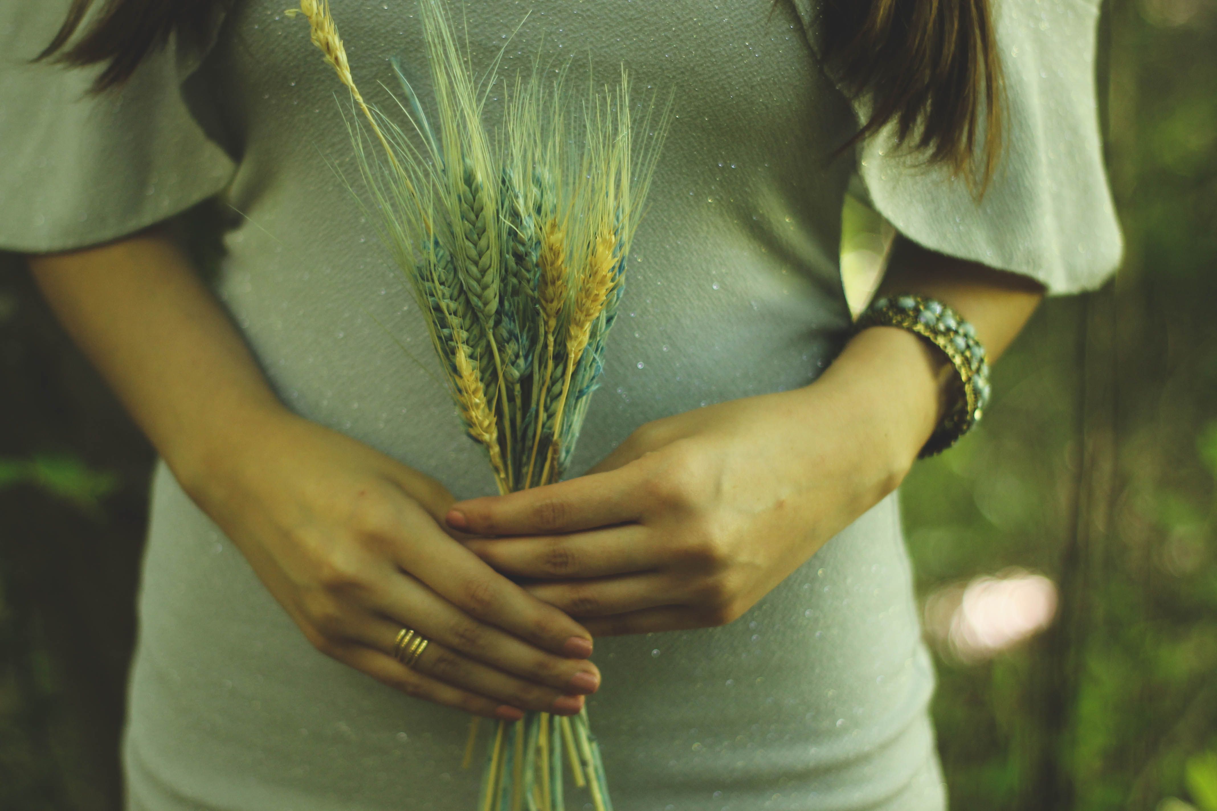 A woman gently holding a small bouquet of wheat in her hands, symbolizing nature and simplicity.