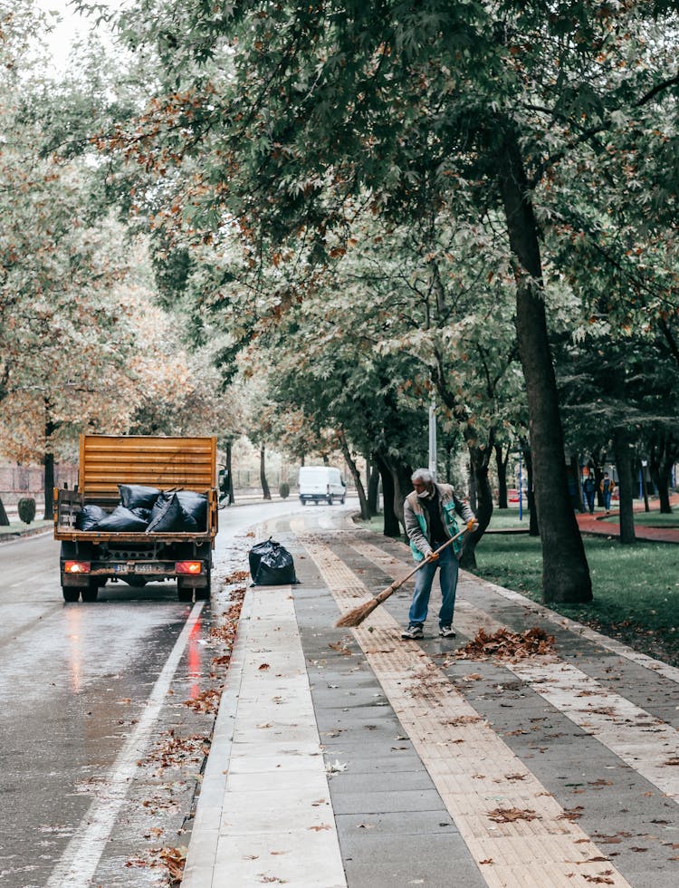 Man Sweeping At The Sidewalk