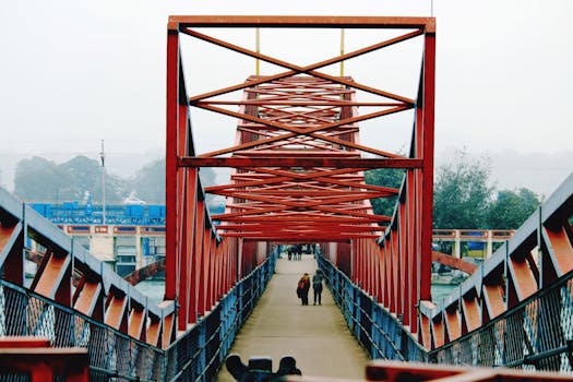 People walking across a red steel bridge in Haridwar, India, showcasing modern infrastructure.