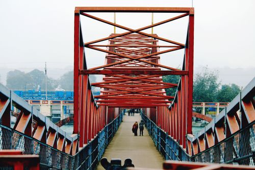 Free People walking across a red steel bridge in Haridwar, India, showcasing modern infrastructure. Stock Photo