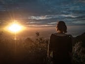 在充满活力的日落中，一个女人的轮廓凝视着郁郁葱葱的宁静风景