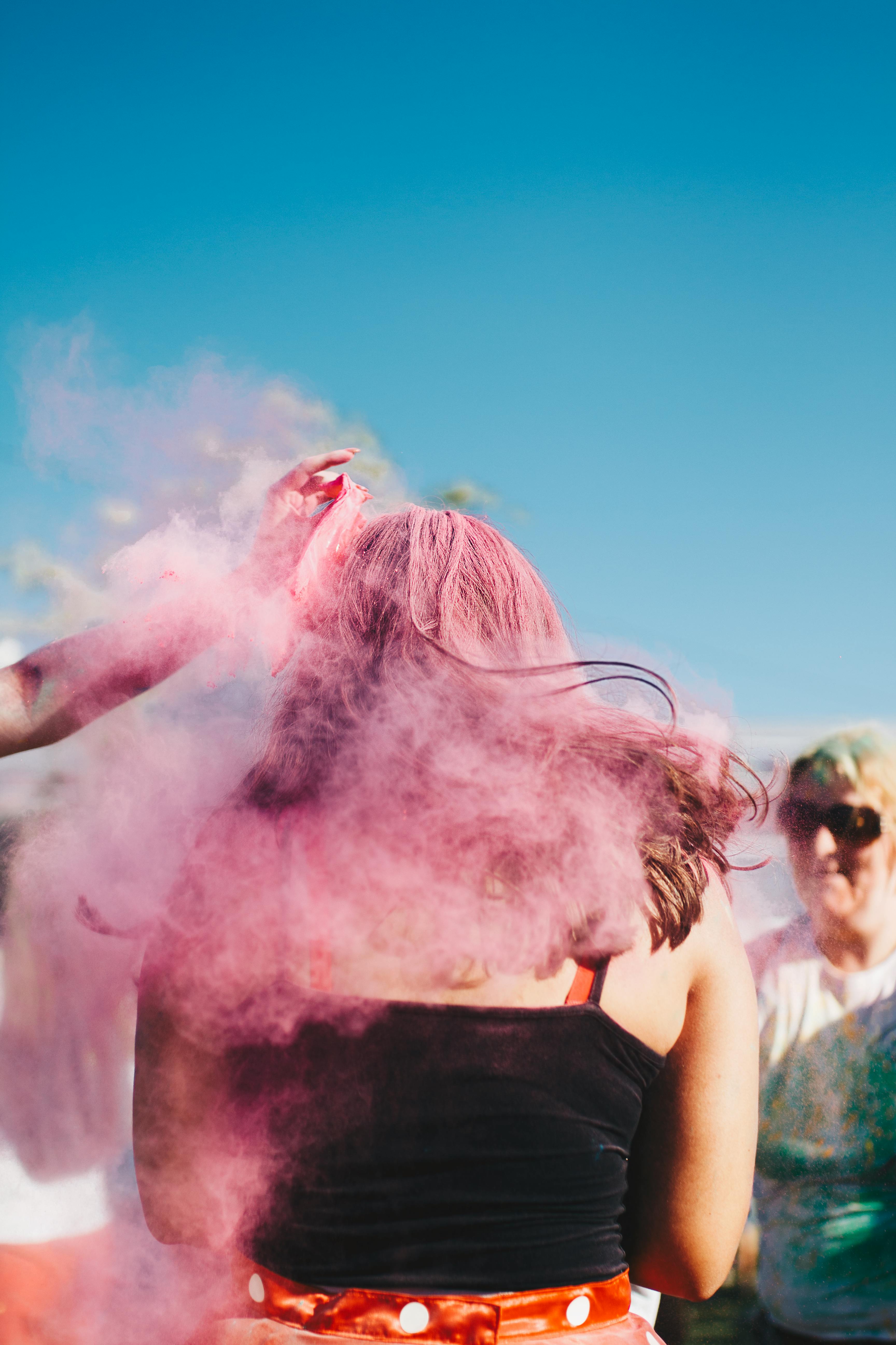 Vibrant outdoor festival with people enjoying pink powder festivities. Perfect for lifestyle and culture themes.