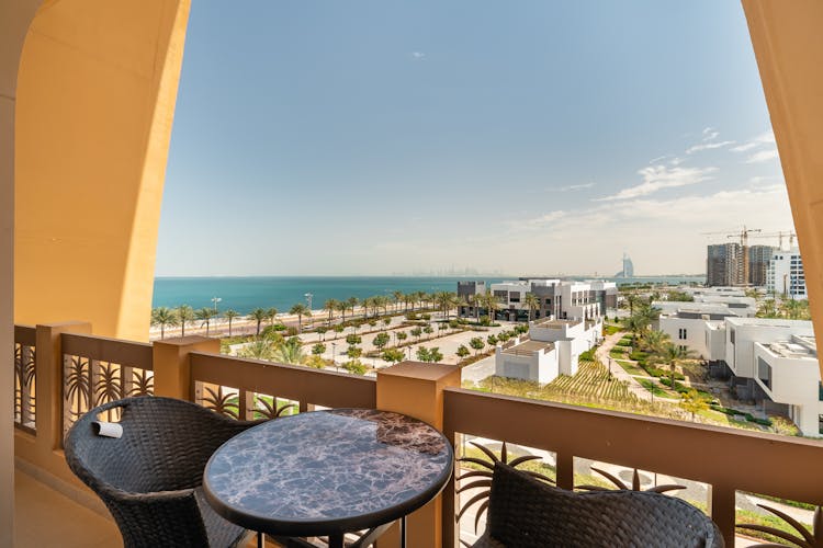 A Table And Chairs On The Balcony With A Beach View