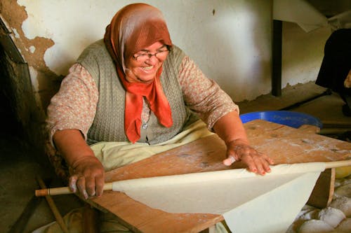Woman Wearing a Headscarf Rolling a Dough
