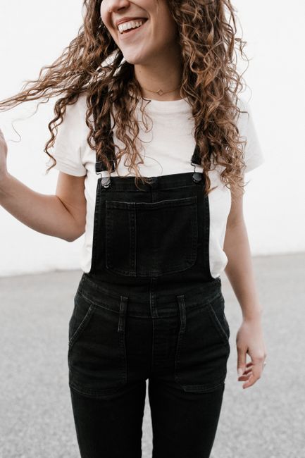 Charming young woman with curly hair in casual outfit, smiling delightfully.