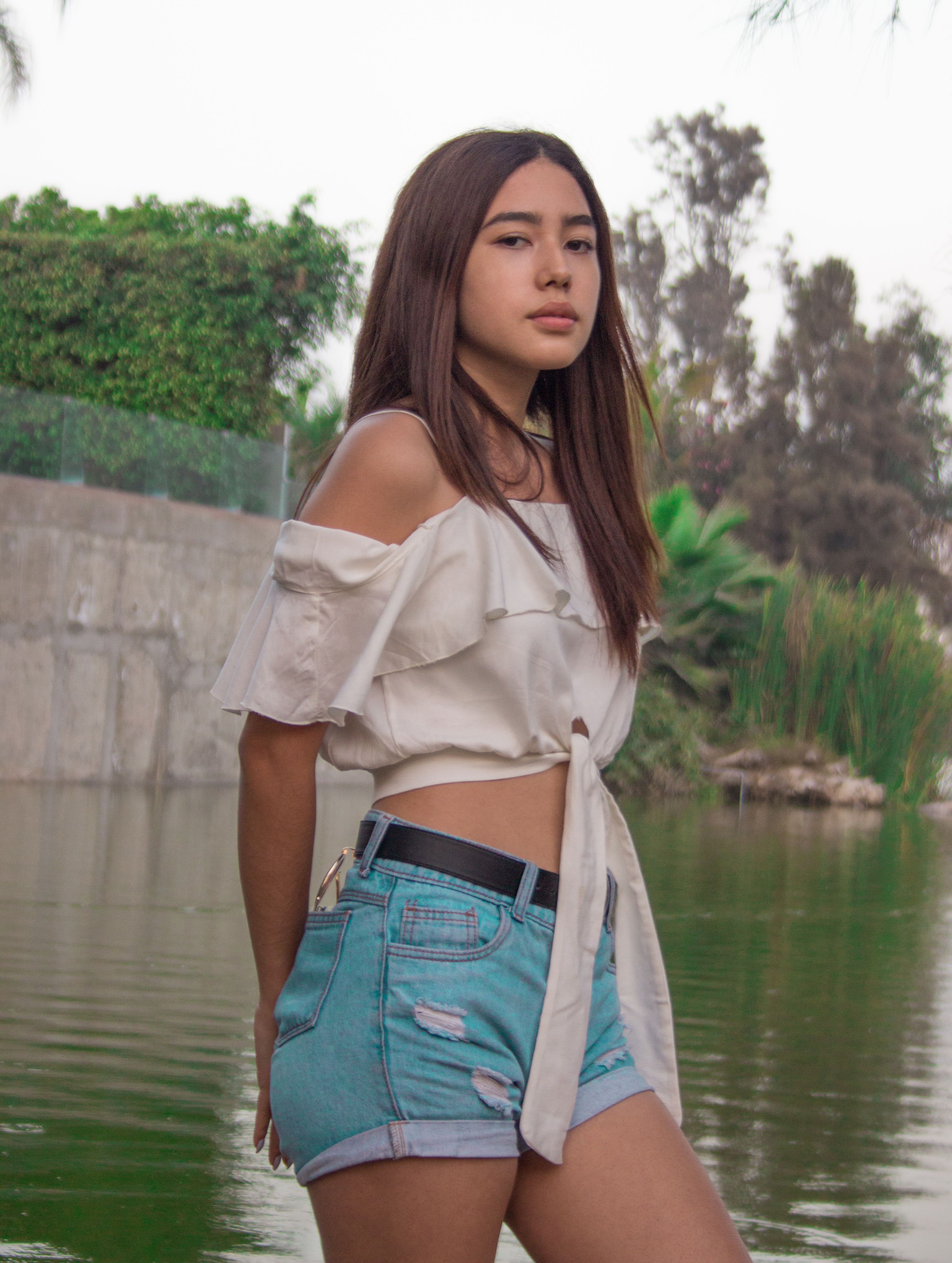 Stylish young woman posing by a serene lagoon in Peru.