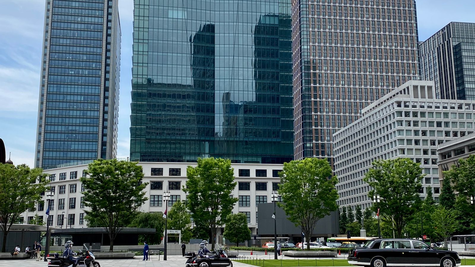 Urban landscape of Chiyoda City, Tokyo featuring modern skyscrapers, greenery, and traffic.